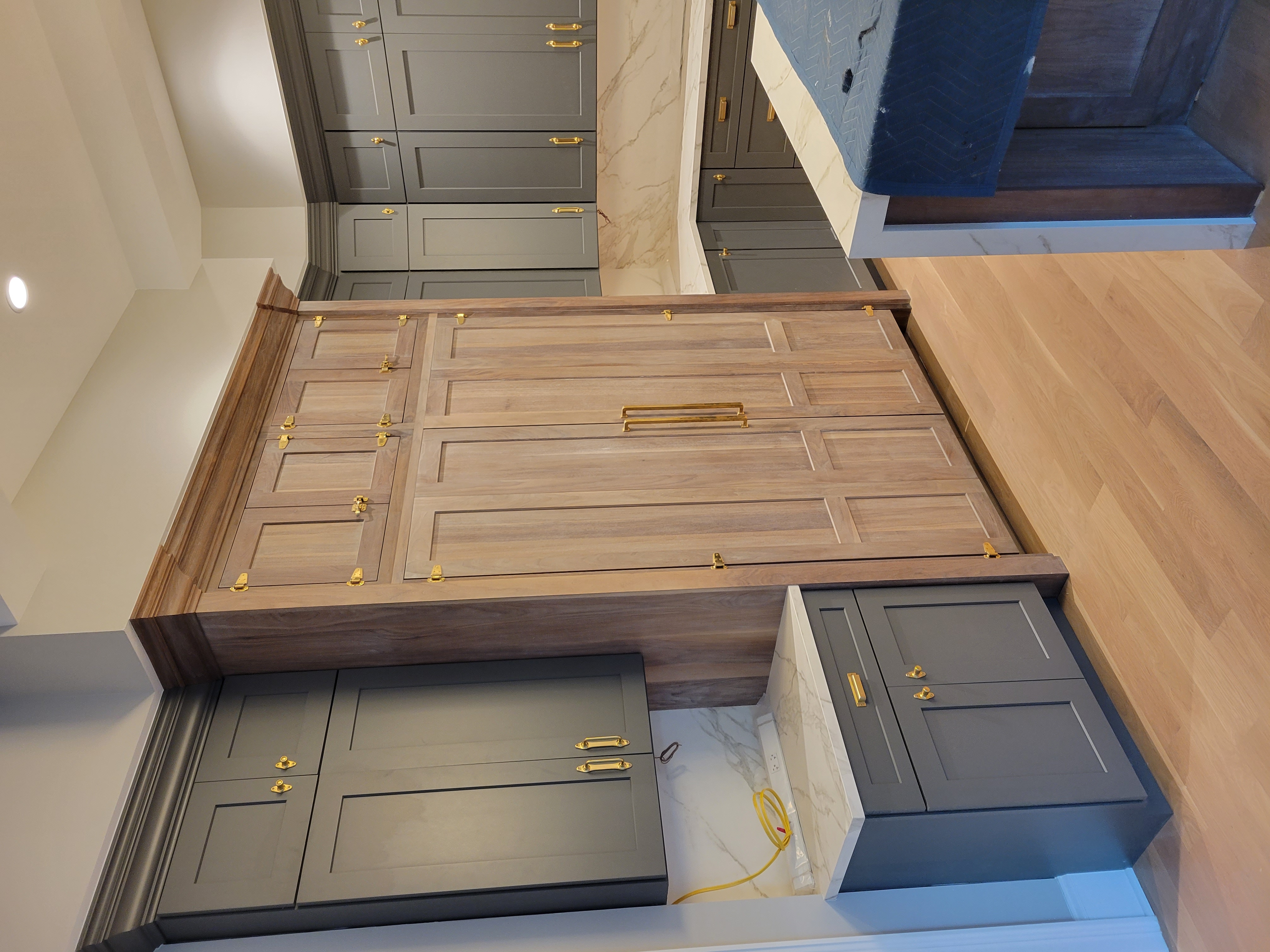 Luxury walk-in closet with walnut built-in refrigerator and gray cabinetry