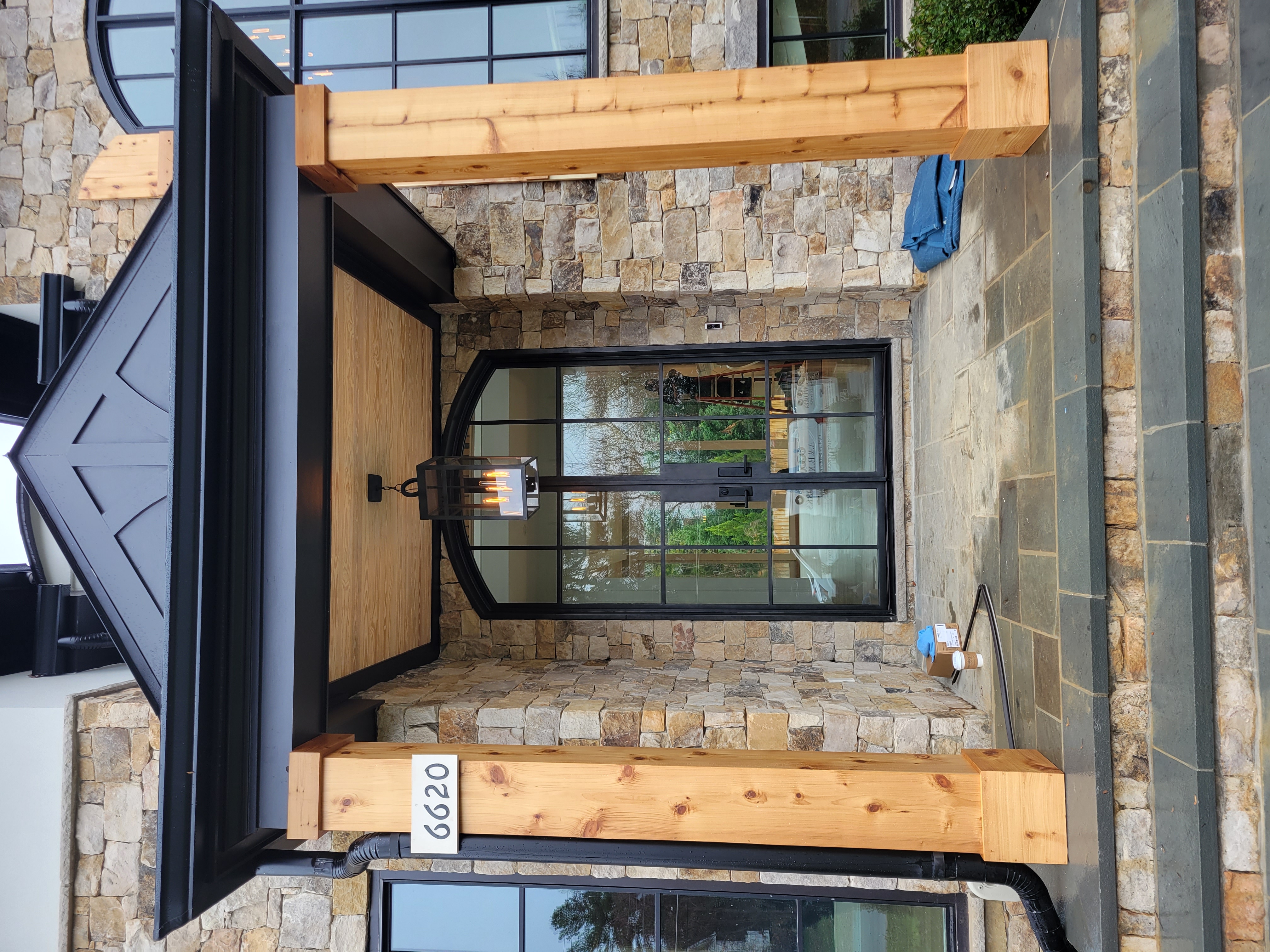 Modern farmhouse entry with stone veneer and cedar beams