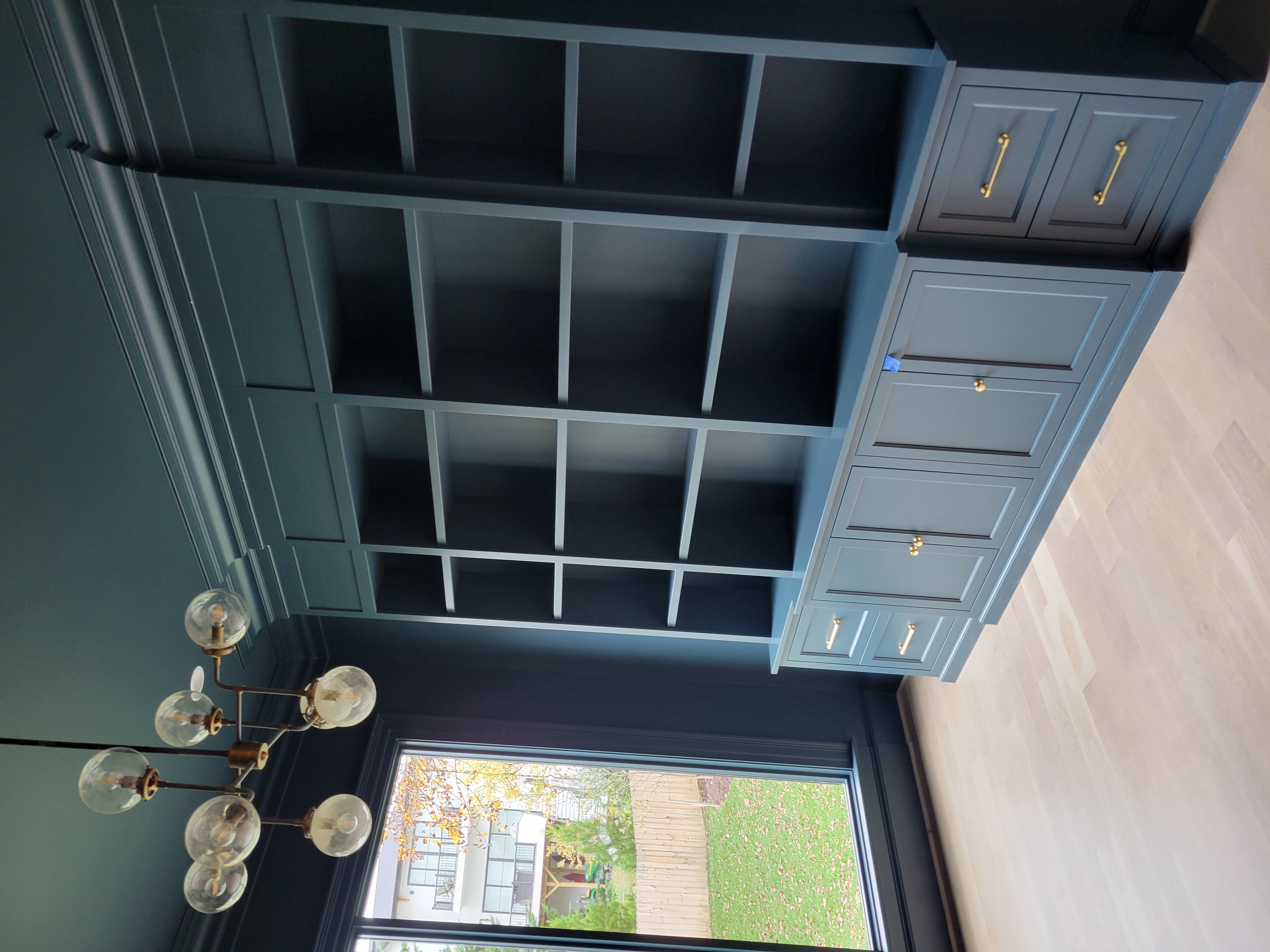 Dark navy built-in library wall with brass hardware
